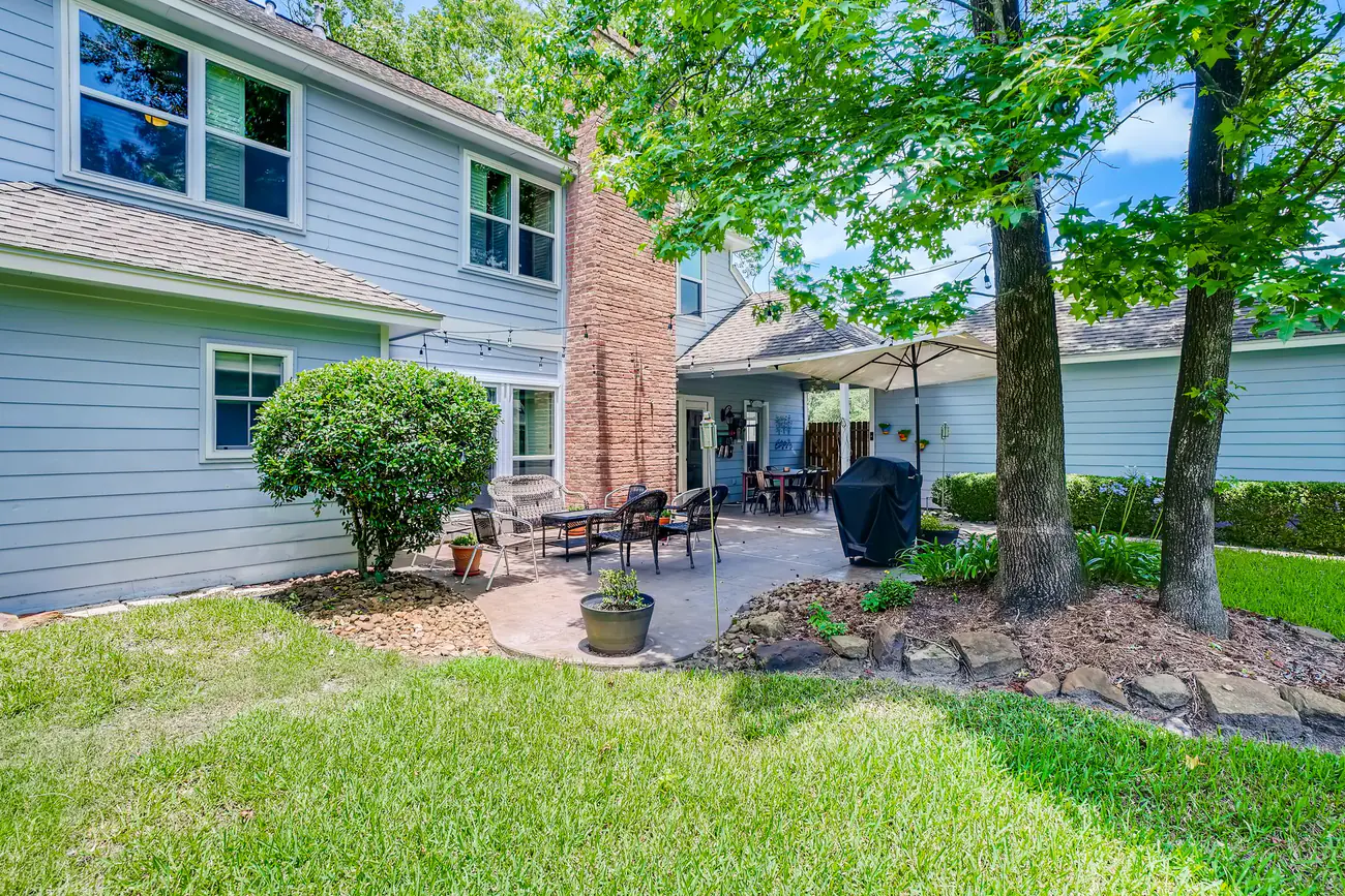 A maintained residential backyard with trimmed shrubs, lawn, and planting beds